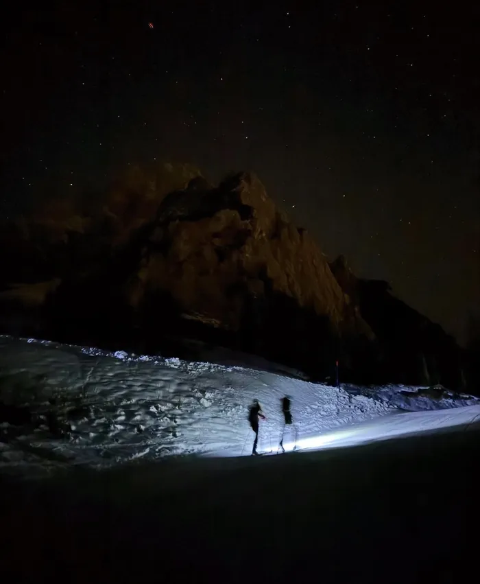 Due scialpinisti in salita sotto le Dolomiti illuminate